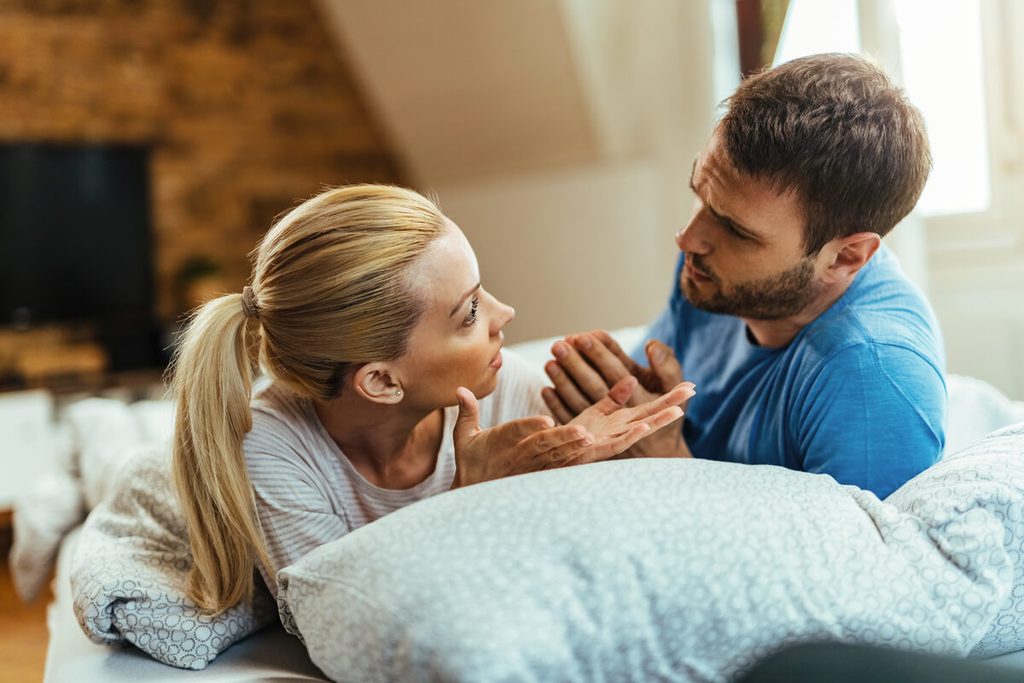 Couple discutant calmement de confort intime et de contraception dans leur salon.