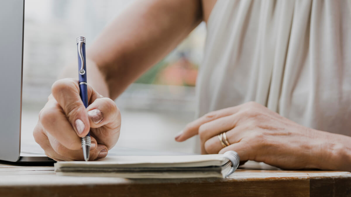 Main écrivant un message manuscrit de réconfort au stylo sur une carte de condoléances sobre.