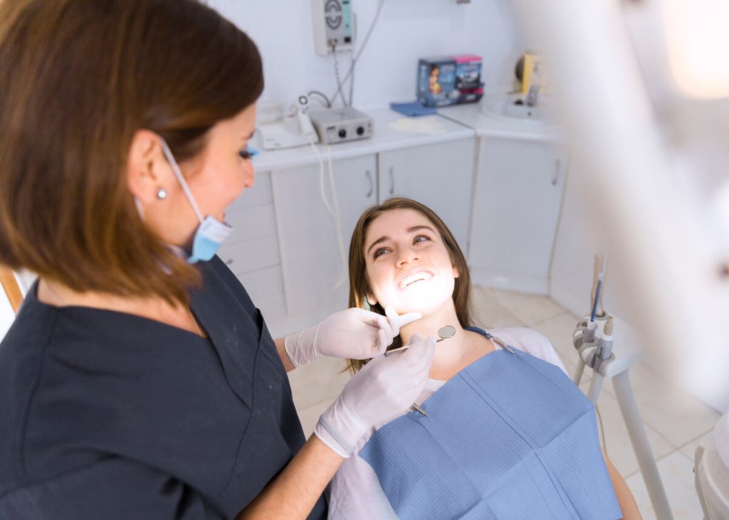 Dentiste auscultant la santé gingivale et l'émail dentaire d'un patient au cabinet.