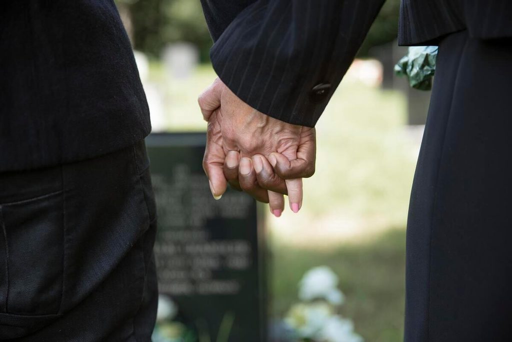 Voir une personne décédée en vrai : ce qu'il faut savoir avant de se décider 4 Deux proches se tenant la main lors d'une veillée funéraire en chambre mortuaire.