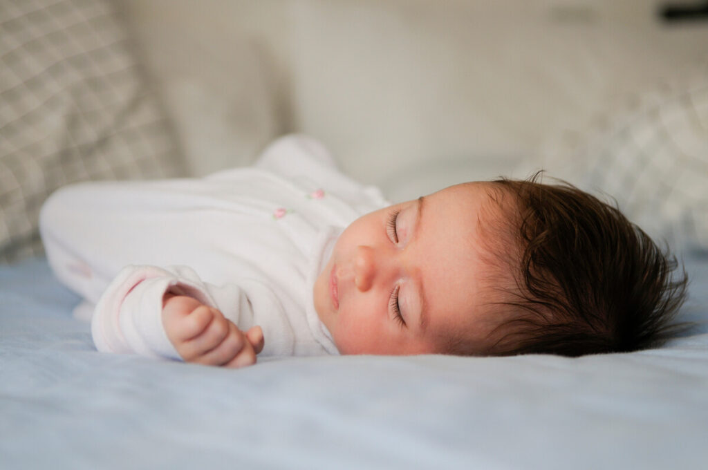 Bébé a le visage froid la nuit : est-ce grave, température et conseils 2 Nourrisson endormi sur le dos dans une gigoteuse bien ajustée dans sa chambre.
