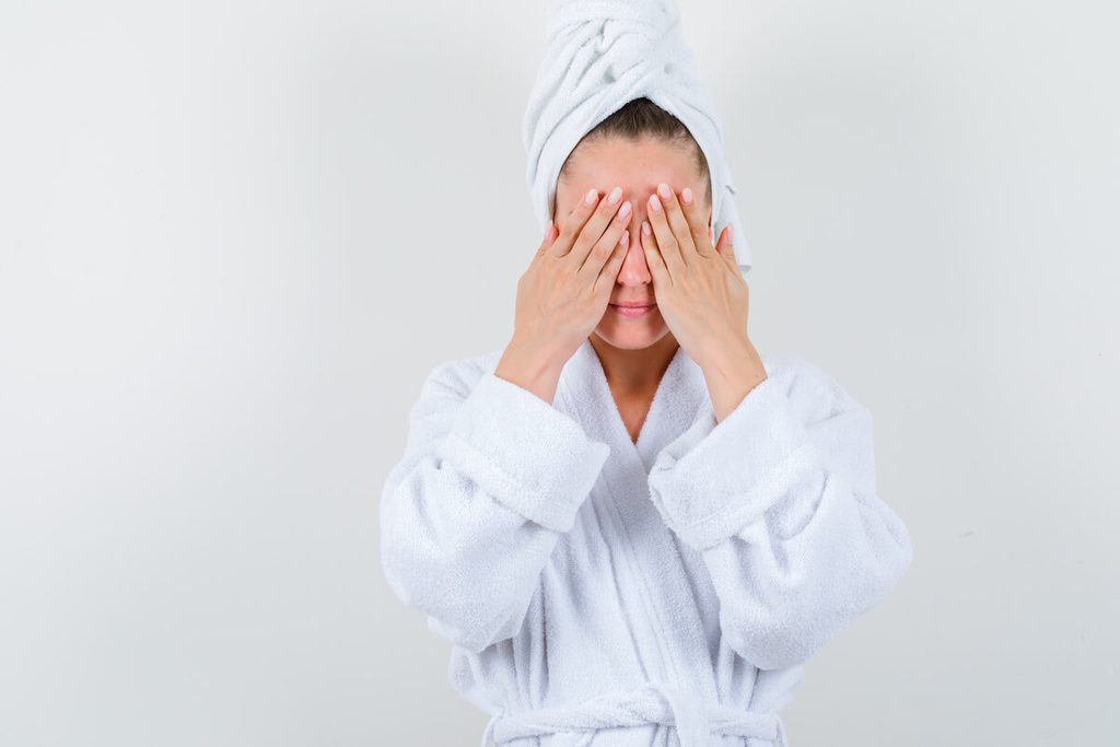 Application d'une compresse d'eau tiède sur les yeux pour fluidifier le sébum des paupières.