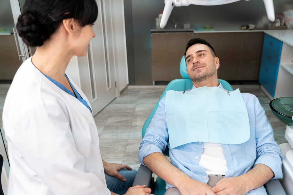 Comment trouver un dentiste facilement près de chez soi : astuces et démarches simples 3 Chirurgien-dentiste recevant un patient dans un cabinet de soins équipé d'un fauteuil médicalisé.