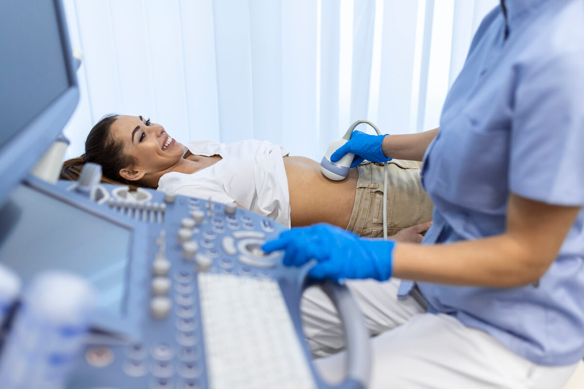 Médecin radiologue réalisant une échographie pelvienne avec sonde pour explorer l'utérus et les ovaires.
