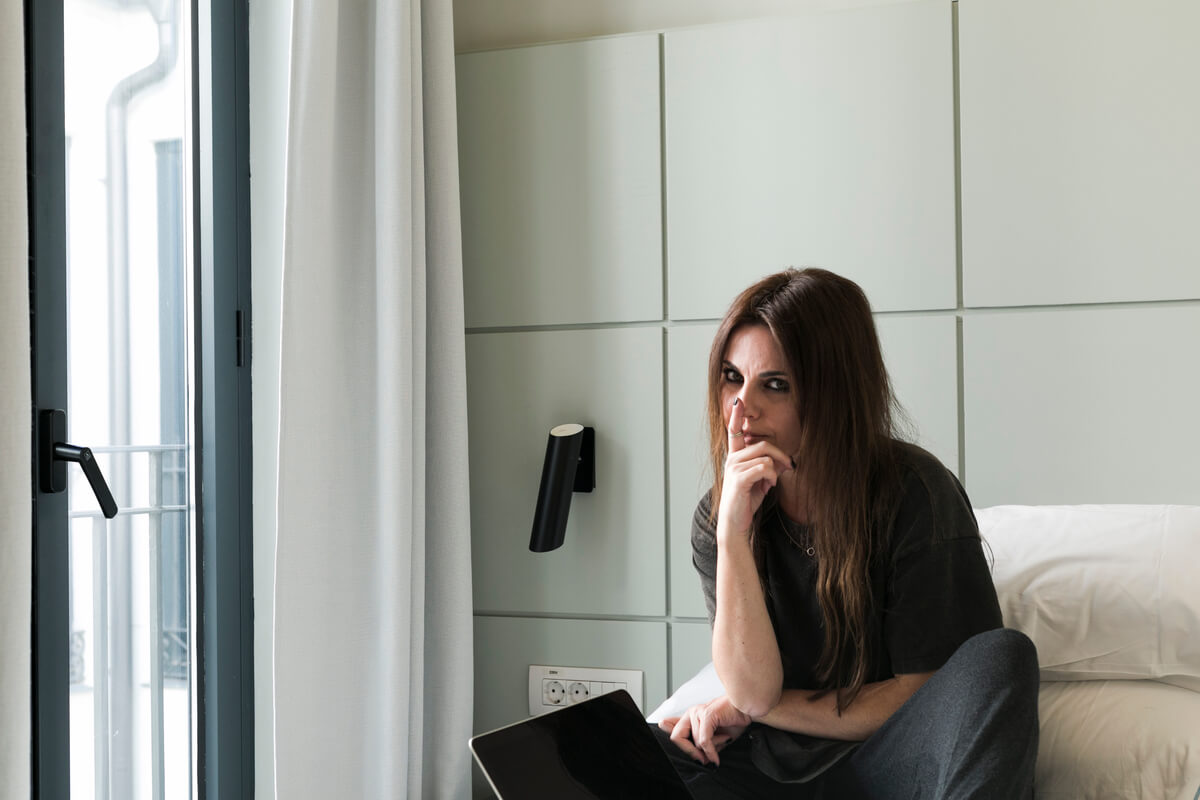 Personne assise pensive près d'une fenêtre ressentant un blocage pour exprimer ses larmes.