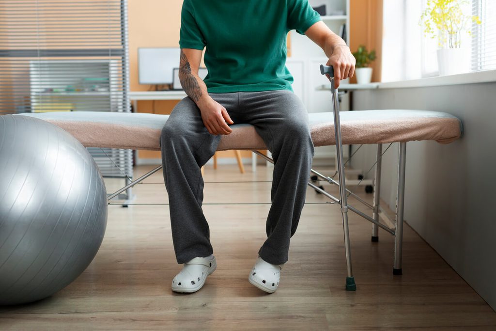 Patient en béquilles réalisant des exercices de flexion de genou avec son kinésithérapeute.