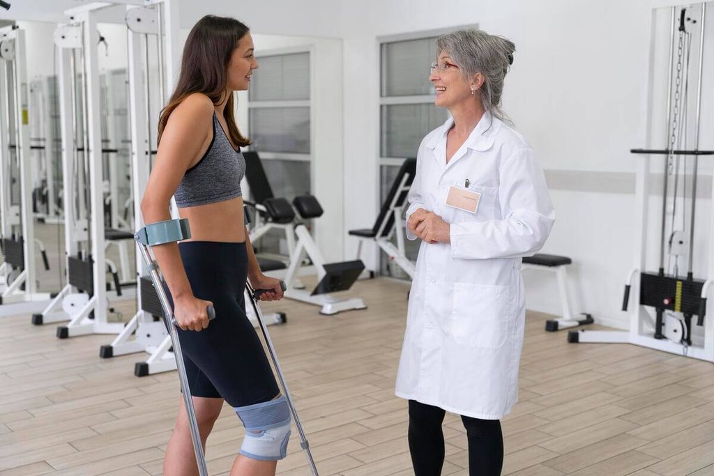 Temps de consolidation d'une fracture du fémur : délais de guérison et reprise de la marche 3 Patient travaillant l'appui et la marche assistée avec son kinésithérapeute après chirurgie de la cuisse.